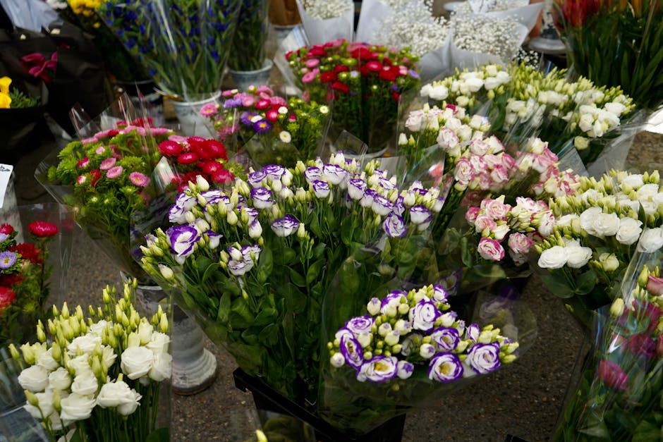 A vibrant display of fresh florist flowers arranged in bouquets and individual stems on a table at Flowers Hornsey. The assortment includes purple and white irises, white lisianthus, pink and white ro